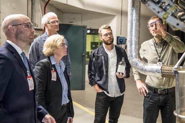 Håkan Schmidt, GKN visar RM12-motorn för fr v Håkan Johansson, Försvarsmaktens Hållbarhetssektion, Ingela Bolin Holmberg, FMV, Torbjörn Hillerström, och Fredrik Lundgren med ett biobränsleprov i handen, båda GKN.